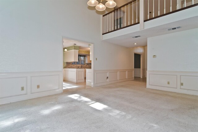 748 Arbor Creek Dr, Desoto, TX 75115 - unfurnished living room with a decorative wall, a chandelier, carpet flooring, a wainscoted wall, and a high ceiling