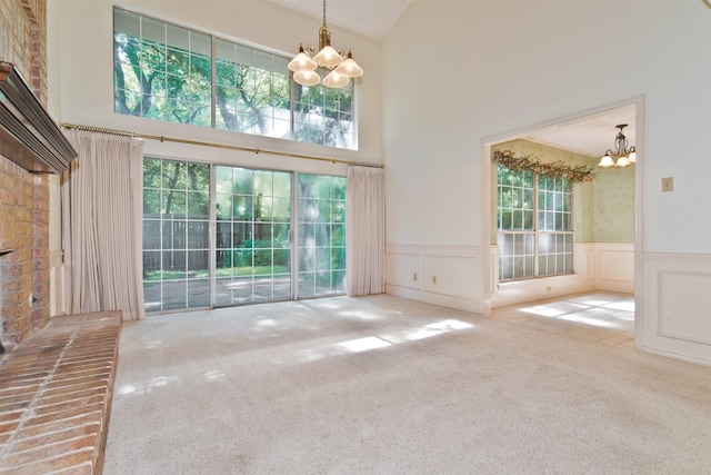 748 Arbor Creek Dr, Desoto, TX 75115 - unfurnished living room with a chandelier, a towering ceiling, healthy amount of natural light, carpet floors, and wainscoting