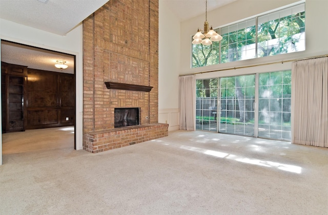 748 Arbor Creek Dr, Desoto, TX 75115 - unfurnished living room with a high ceiling, carpet flooring, a chandelier, a brick fireplace, and a decorative wall