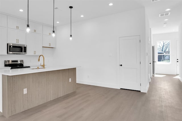 408 Grayson, Leonard, TX 75452 - kitchen with appliances with stainless steel finishes, light wood finished floors, light countertops, a kitchen island with sink, and white cabinets