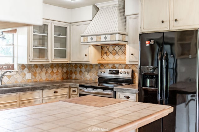 2306 County Road 475, Anson, TX 79501 - kitchen with black fridge with ice dispenser, custom exhaust hood, stainless steel range with electric stovetop, and tasteful backsplash