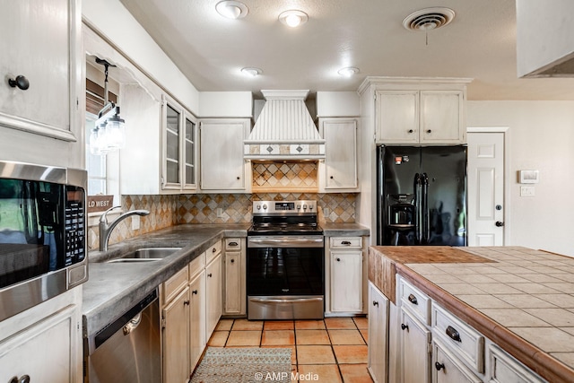 2306 County Road 475, Anson, TX 79501 - kitchen with stainless steel appliances, custom exhaust hood, decorative backsplash, glass insert cabinets, and light tile patterned flooring