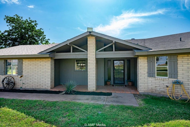 2306 County Road 475, Anson, TX 79501 - doorway to property featuring brick siding, a lawn, and a shingled roof