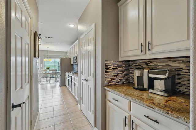 1330 Scarboro Hills Ln, Rockwall, TX 75087 - kitchen featuring appliances with stainless steel finishes, light tile patterned flooring, decorative backsplash, stone countertops, and white cabinetry