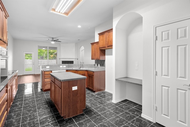 908 Trinity Dr, Lancaster, TX 75146 - kitchen featuring a fireplace, brown cabinets, a center island, ceiling fan, and arched walkways