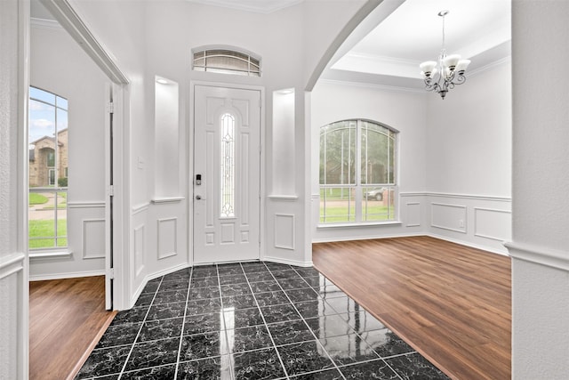 908 Trinity Dr, Lancaster, TX 75146 - entrance foyer featuring crown molding, a chandelier, a decorative wall, dark marble finish floors, and wainscoting