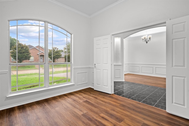 908 Trinity Dr, Lancaster, TX 75146 - empty room featuring a chandelier, ornamental molding, dark wood-style floors, a wainscoted wall, and arched walkways
