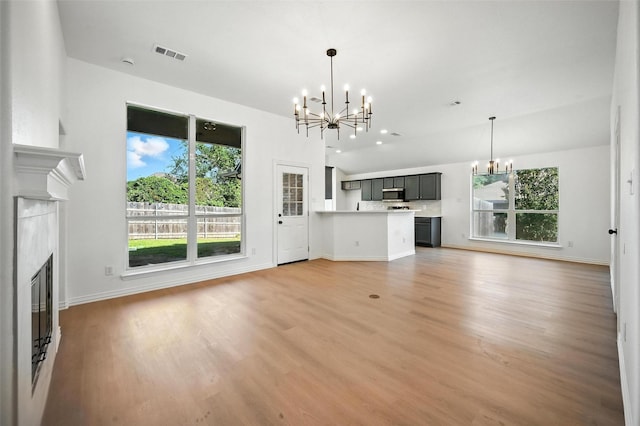 713 Madeline Ct, Azle, TX 76020 - unfurnished living room featuring a chandelier, a fireplace, and light wood-style flooring