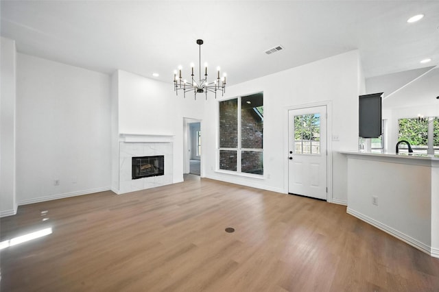 713 Madeline Ct, Azle, TX 76020 - unfurnished living room with a chandelier, wood finished floors, recessed lighting, and a high end fireplace