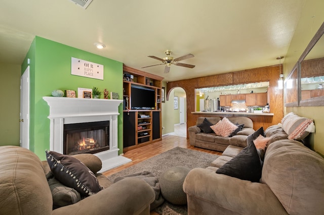 3060 Saint Nicholas Dr, Dallas, TX 75233 - living area featuring ceiling fan, wood finished floors, a glass covered fireplace, and arched walkways
