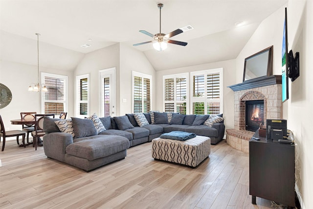 9809 Trinity Dr, Little Elm, TX 75068 - living area featuring vaulted ceiling, ceiling fan, light wood finished floors, a chandelier, and a glass covered fireplace