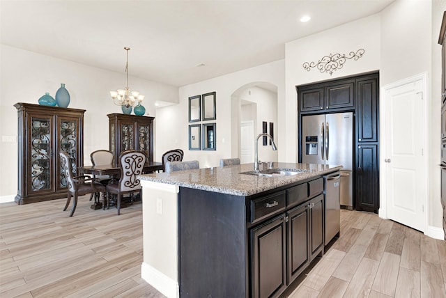 9809 Trinity Dr, Little Elm, TX 75068 - kitchen featuring arched walkways, stainless steel dishwasher, light stone countertops, light wood-style floors, and recessed lighting