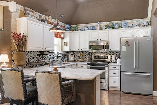 3901 Woodside Dr, Arlington, TX 76016 - kitchen featuring appliances with stainless steel finishes, a peninsula, tasteful backsplash, white cabinets, and vaulted ceiling