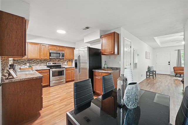 515 Signal Hill Ct S, Fort Worth, TX 76112 - kitchen with appliances with stainless steel finishes, light wood-style floors, backsplash, and brown cabinets