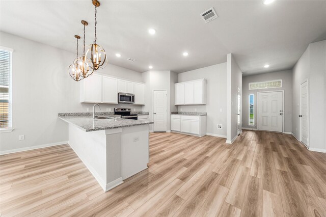 4020 Centerfire Rd, Waco, TX 76705 - kitchen with stainless steel appliances, a peninsula, recessed lighting, light wood finished floors, and white cabinetry