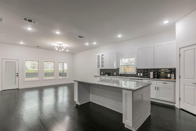 407 Dubois Ave, Dallas, TX 75203 - kitchen with decorative backsplash, a kitchen island, glass insert cabinets, white cabinets, and light stone counters