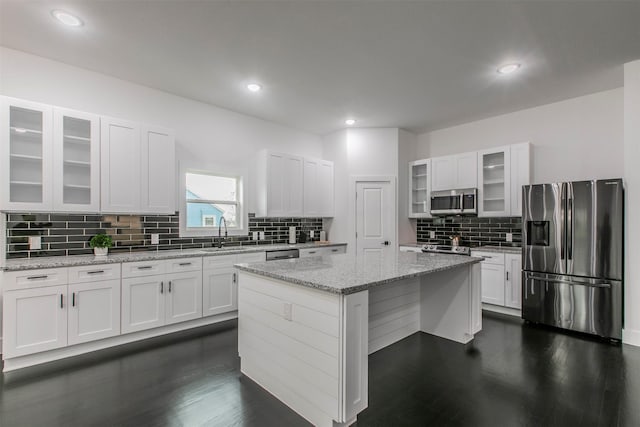 407 Dubois Ave, Dallas, TX 75203 - kitchen with stainless steel appliances, a center island, dark wood finished floors, tasteful backsplash, and white cabinetry