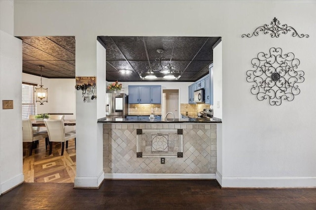 1701 Prairie Creek Ct, Garland, TX 75040 - kitchen featuring blue cabinetry, a chandelier, appliances with stainless steel finishes, dark countertops, and dark wood-type flooring