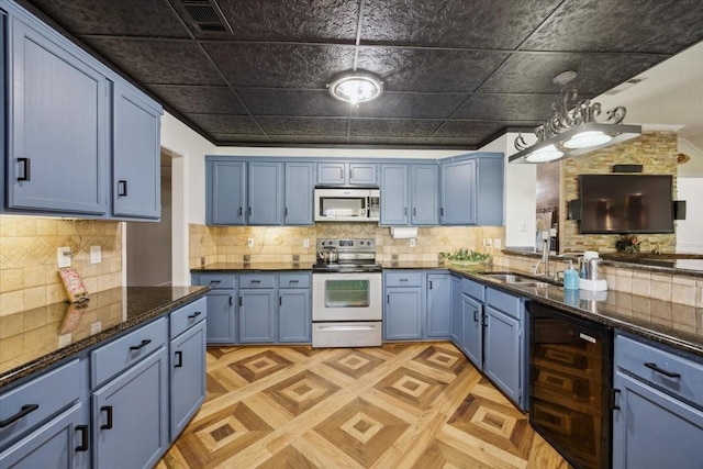 1701 Prairie Creek Ct, Garland, TX 75040 - kitchen with stainless steel appliances, blue cabinets, beverage cooler, decorative backsplash, and dark stone counters