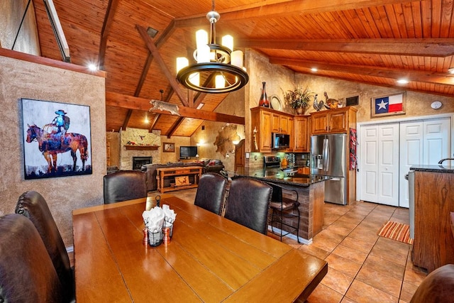 188 Hacienda, Pottsboro, TX 75076 - dining space with a wood ceiling with exposed beams, high vaulted ceiling, light tile patterned floors, a chandelier, and a stone fireplace