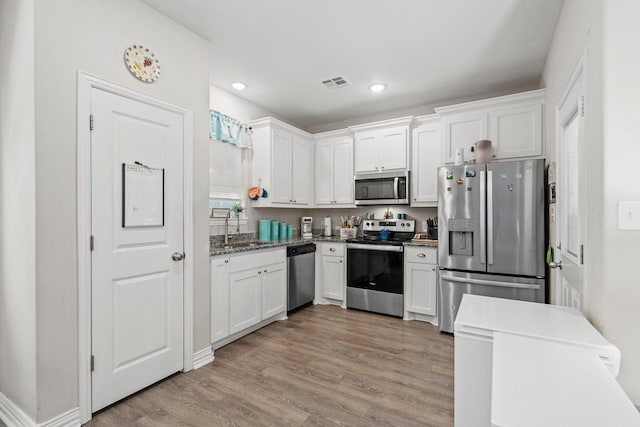 409 N Houston Ave, Denison, TX 75021 - kitchen with stainless steel appliances, white cabinets, light wood-type flooring, and recessed lighting