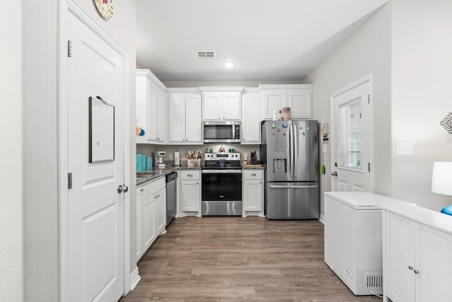 409 N Houston Ave, Denison, TX 75021 - kitchen featuring appliances with stainless steel finishes, white cabinetry, wood finished floors, and recessed lighting