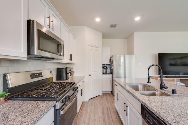 627 Beltrand Ln, Fate, TX 75087 - kitchen featuring appliances with stainless steel finishes, white cabinetry, light wood finished floors, decorative backsplash, and light stone counters