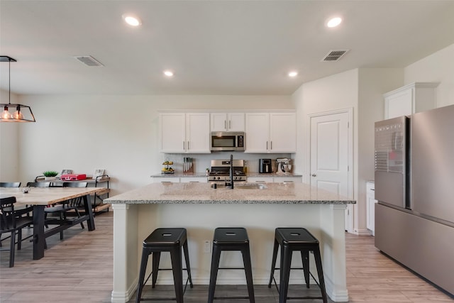 627 Beltrand Ln, Fate, TX 75087 - kitchen with stainless steel appliances, a breakfast bar, light wood-style floors, white cabinetry, and recessed lighting
