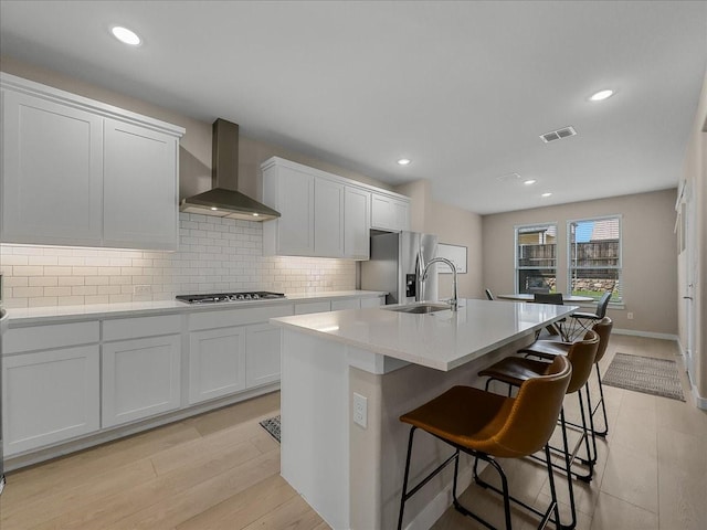 413 Coyote Creek Dr, Lavon, TX 75166 - kitchen featuring wall chimney exhaust hood, appliances with stainless steel finishes, an island with sink, tasteful backsplash, and white cabinets