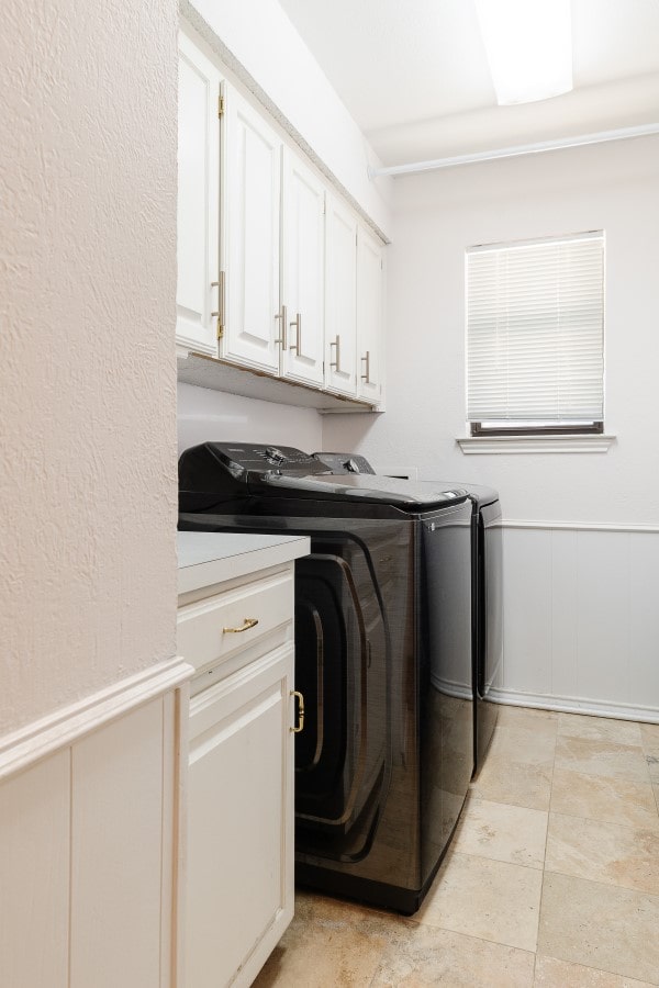 2304 Wakeforest Ct, Arlington, TX 76012 - laundry area featuring washing machine and dryer, cabinet space, and a decorative wall