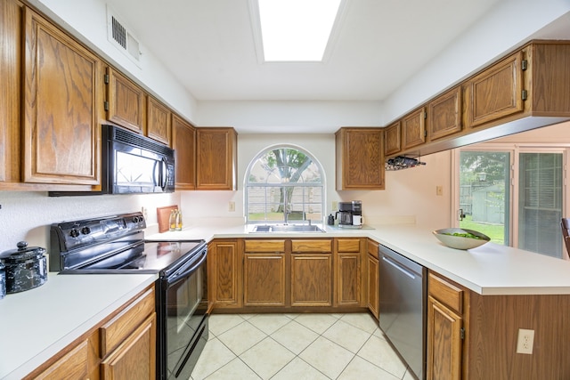 113 Windmill Ridge Dr, Rockwall, TX 75032 - kitchen with black appliances, a peninsula, light tile patterned floors, light countertops, and brown cabinets