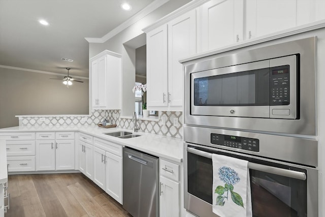 1057 Cornell Dr, Carrollton, TX 75007 - kitchen featuring appliances with stainless steel finishes, crown molding, light countertops, white cabinets, and backsplash