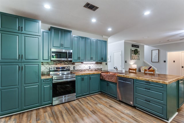 412 Paradise Canyon Cir, Paradise, TX 76073 - kitchen featuring stainless steel appliances, a peninsula, crown molding, decorative backsplash, and wood finished floors