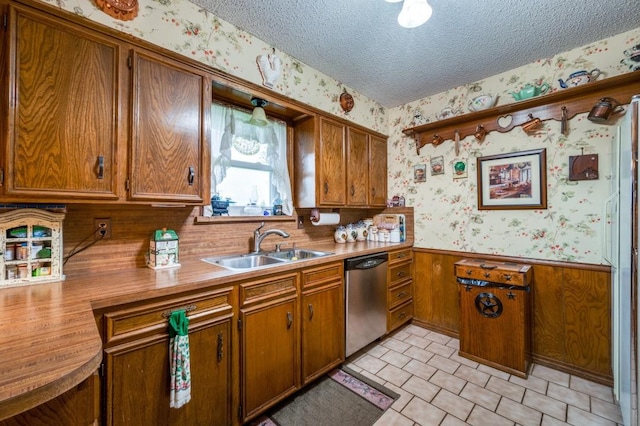 12869 Fm 1385, Pilot Point, TX 76258 - kitchen featuring wallpapered walls, dishwasher, a wainscoted wall, brown cabinets, and a textured ceiling