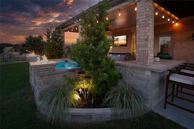 12953 Hurricane Ln, Fort Worth, TX 76244 - pool at dusk featuring a bar, exterior kitchen, ceiling fan, and a hot tub