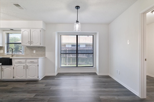 2206 Spring Leaf Dr, Carrollton, TX 75006 - kitchen with white cabinetry, light countertops, dark wood-style flooring, tasteful backsplash, and pendant lighting