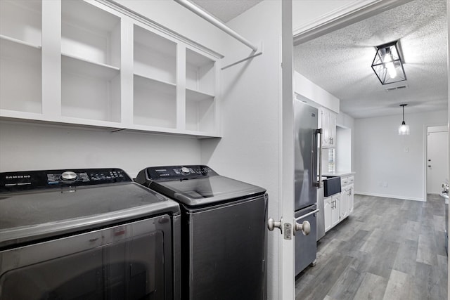 2206 Spring Leaf Dr, Carrollton, TX 75006 - washroom with a textured ceiling, washer and clothes dryer, and wood finished floors
