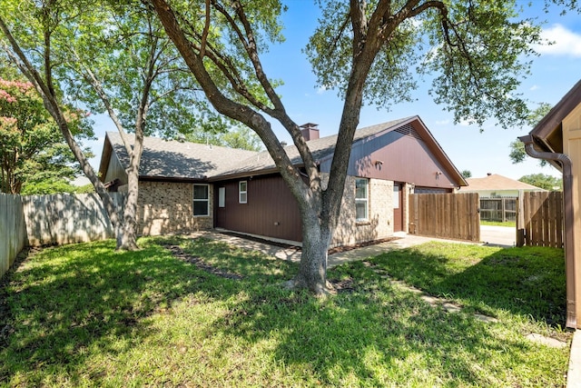2206 Spring Leaf Dr, Carrollton, TX 75006 - back of property featuring a chimney, a fenced backyard, and brick siding