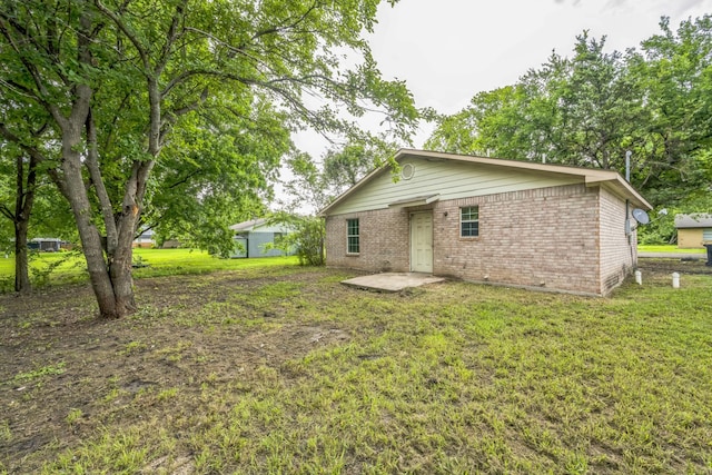 207 N 1st St, Crandall, TX 75114 - back of property featuring brick siding, a lawn, and a patio area