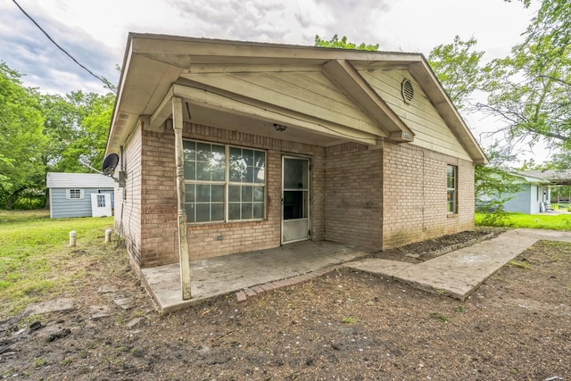 207 N 1st St, Crandall, TX 75114 - rear view of property featuring a patio, brick siding, a yard, and an outdoor structure