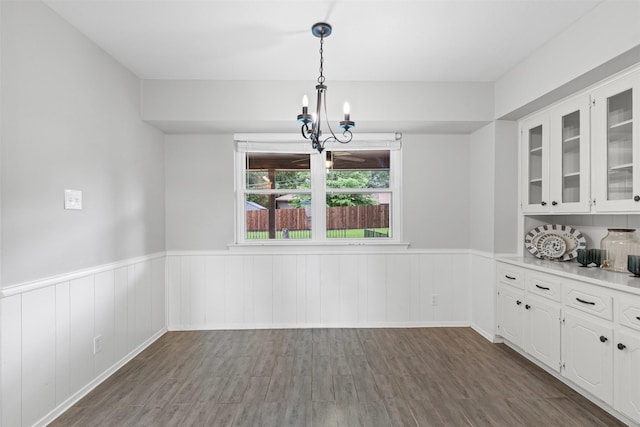 6767 Winifred Dr, Fort Worth, TX 76133 - unfurnished dining area with a wainscoted wall, a chandelier, and dark wood finished floors