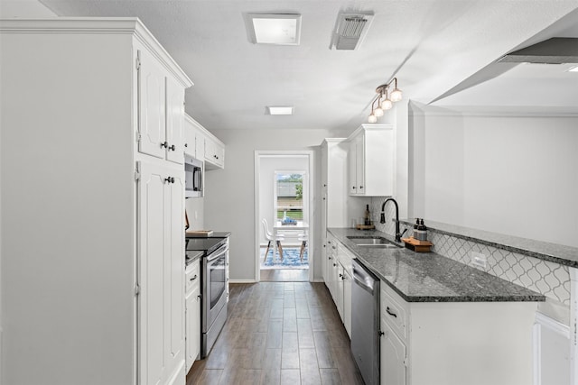 6767 Winifred Dr, Fort Worth, TX 76133 - kitchen with stainless steel appliances, white cabinetry, dark wood-style flooring, dark stone counters, and a peninsula