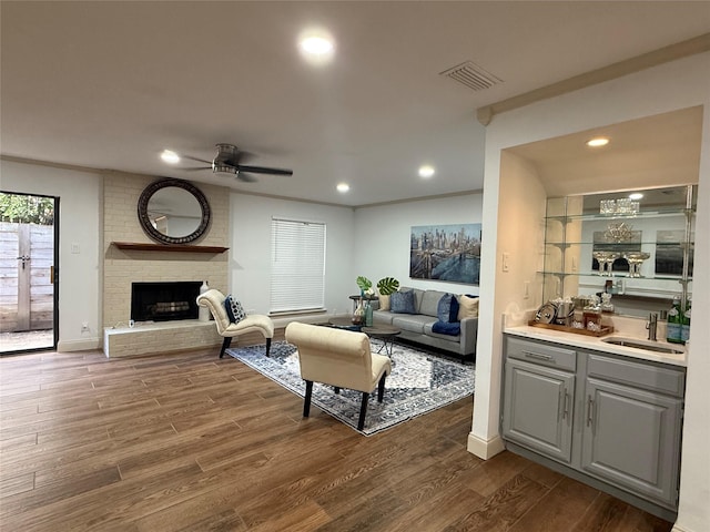 2761 Stonecreek Dr, Carrollton, TX 75006 - living area featuring a ceiling fan, dark wood-type flooring, a fireplace, bar with sink, and recessed lighting