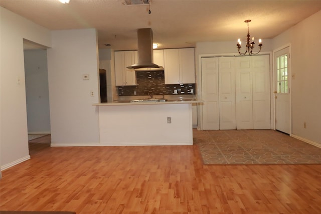 517 Annapolis Dr, Fort Worth, TX 76108 - kitchen with island range hood, light wood-style flooring, white cabinets, backsplash, and a chandelier