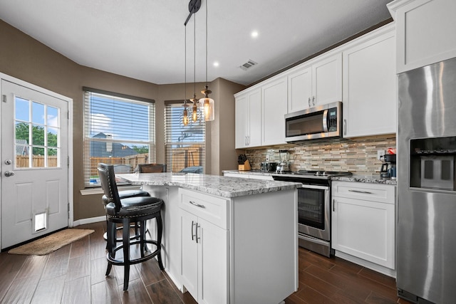 8534 Pebblebrook Dr, Frisco, TX 75034 - kitchen with appliances with stainless steel finishes, a center island, decorative backsplash, recessed lighting, and light stone counters