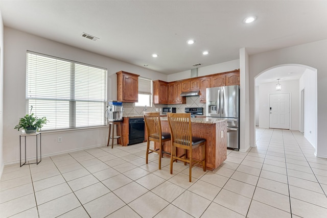 511 Poplar Vista Ln, Arlington, TX 76002 - kitchen with stainless steel appliances, arched walkways, under cabinet range hood, a center island, and tasteful backsplash