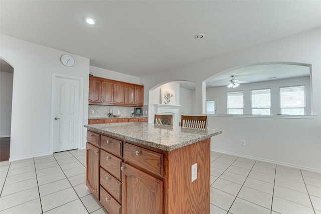 511 Poplar Vista Ln, Arlington, TX 76002 - kitchen with light tile patterned floors, decorative backsplash, a center island, ceiling fan, and light stone counters