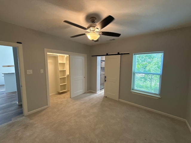 1510 W Woodard St, Denison, TX 75020 - unfurnished bedroom with a barn door, light colored carpet, a spacious closet, a closet, and ceiling fan