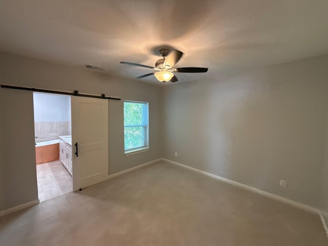 1510 W Woodard St, Denison, TX 75020 - unfurnished bedroom featuring ensuite bathroom, a ceiling fan, and a barn door