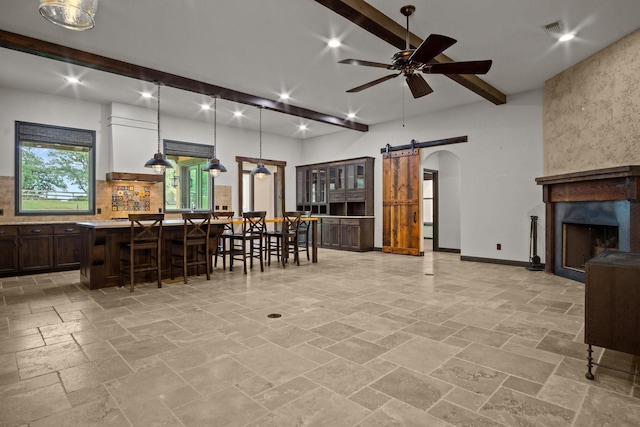 101 Goldfinch Ln, Weatherford, TX 76088 - kitchen featuring a barn door, ceiling fan, decorative backsplash, a breakfast bar area, and light countertops